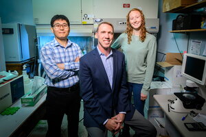Three members of the research team pose together, two standing and Hergenrother seated, in a lab on campus.