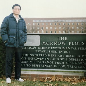 Chuanjing Xu standing next to the brick sign at the Morrow Plots on the UIUC campus.