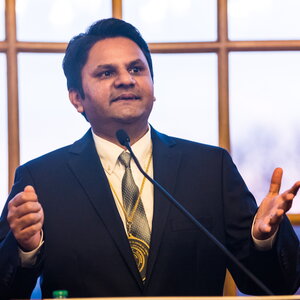 Prashant Jain speaking in front of a large window in the Illini Union