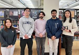 Five of the winners and finalists stand side by side in the library with bookshelves in the background.