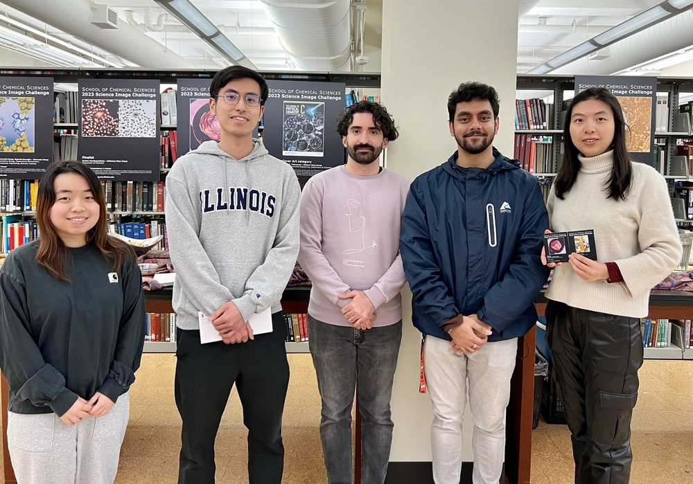 Five of the winners and finalists stand side by side in the library with bookshelves in the background.