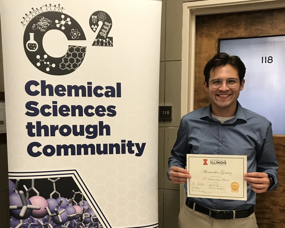 Student holding an award certificate standing next to a vertical banner