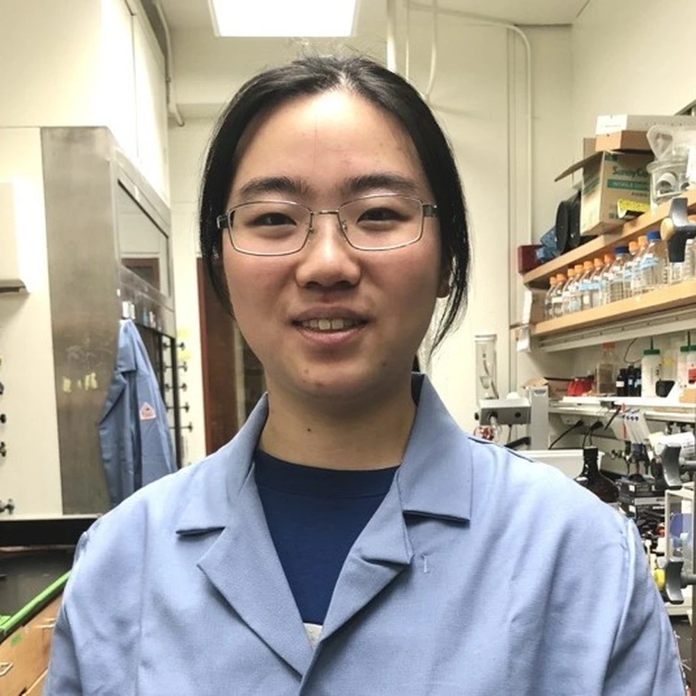 Head shot of Chang Jiang in a blue lab coat in a lab