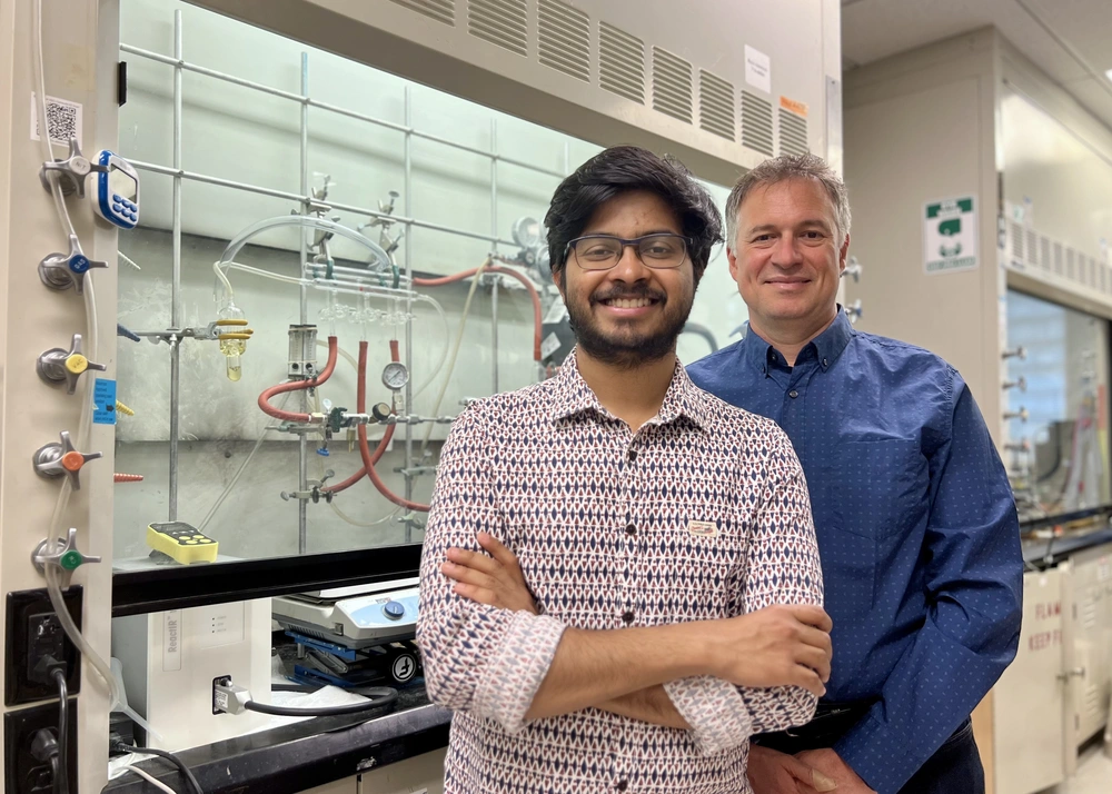 Shounak Nath and Liviu Mirica stand together in front equipment in a chemistry lab