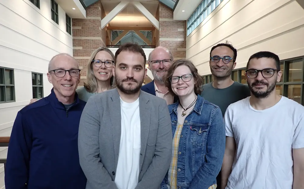 Group of researchers stand side by side in atrium of Beckman Institute.