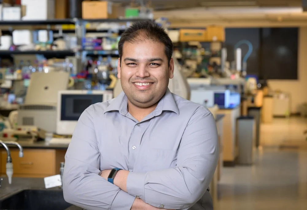 Angad Mehta standing in a lab with arms crossed in front of him