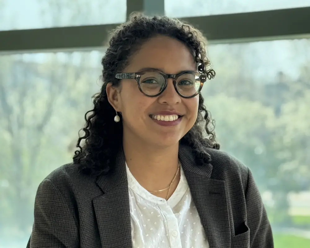 Head shot of Viviana Palacio-Betancur standing in front of a wall of glass windows