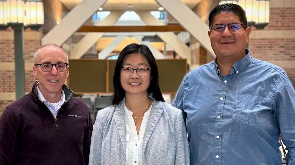 Three people standing side by side in the Beckman atrium