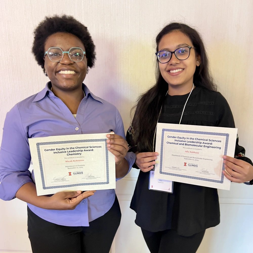 Picture of two people standing side by side holding award certificates