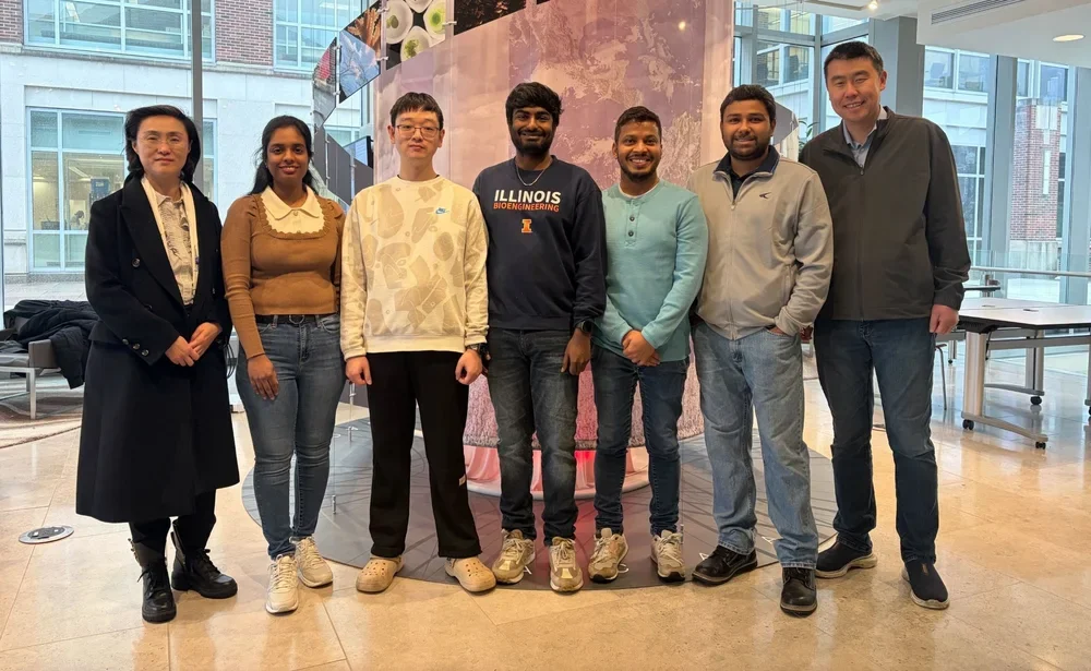 Group of researchers standing side by side in the atrium of the Carl Woese Center for Genomic Biology.