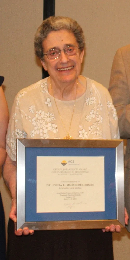 Person standing and holding a framed award