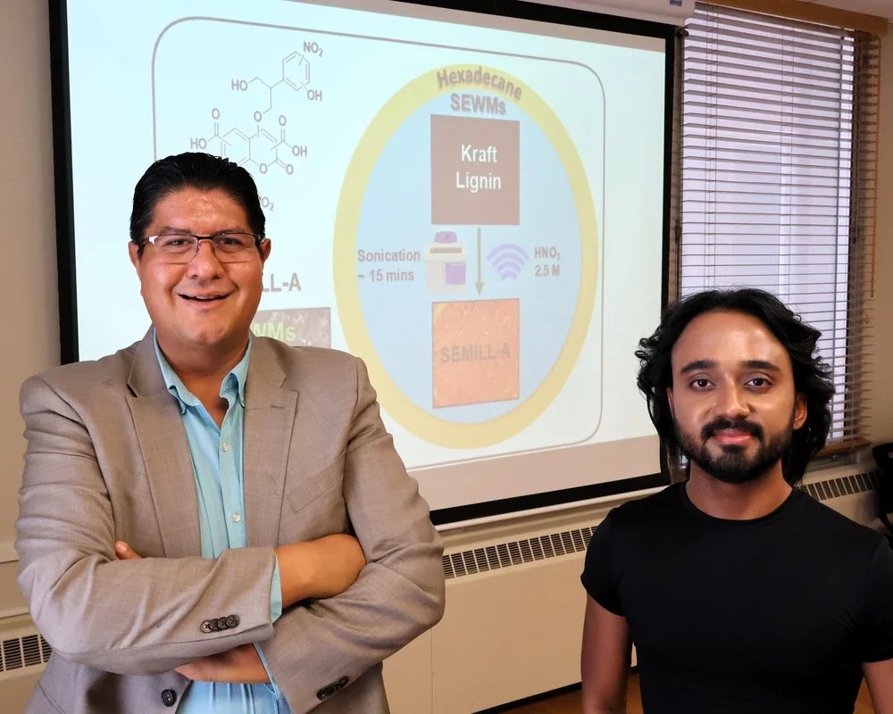 Joaquin Rodriguez-Lopez and Riyo Das standing in front of an overhead screen.