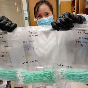 Jia En Aw, a Beckman Institute graduate research assistant and aerospace engineering student, holds 500 swabs being sent for testing