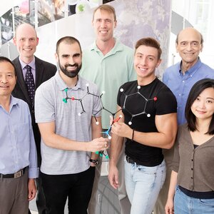 Group photo of the research team with two team members in middle front holding a molecular structure.