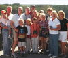 Dr. Milligan and 13 of his family members stand in a group in a location at Yellowstone overlooking a wooded area.