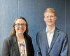 Photo of two people standing next to each other in front of a blue background