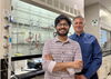Shounak Nath and Liviu Mirica stand together in front equipment in a chemistry lab