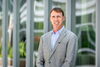 Paul Hergenrother stands in front of a building with tall windows