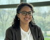 Head shot of Viviana Palacio-Betancur standing in front of a wall of glass windows