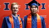 Strand and Yang in graduation regalia on an orange Block I background 