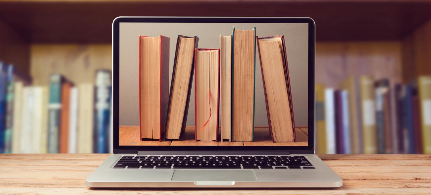 Photo of a laptop and books on shelves