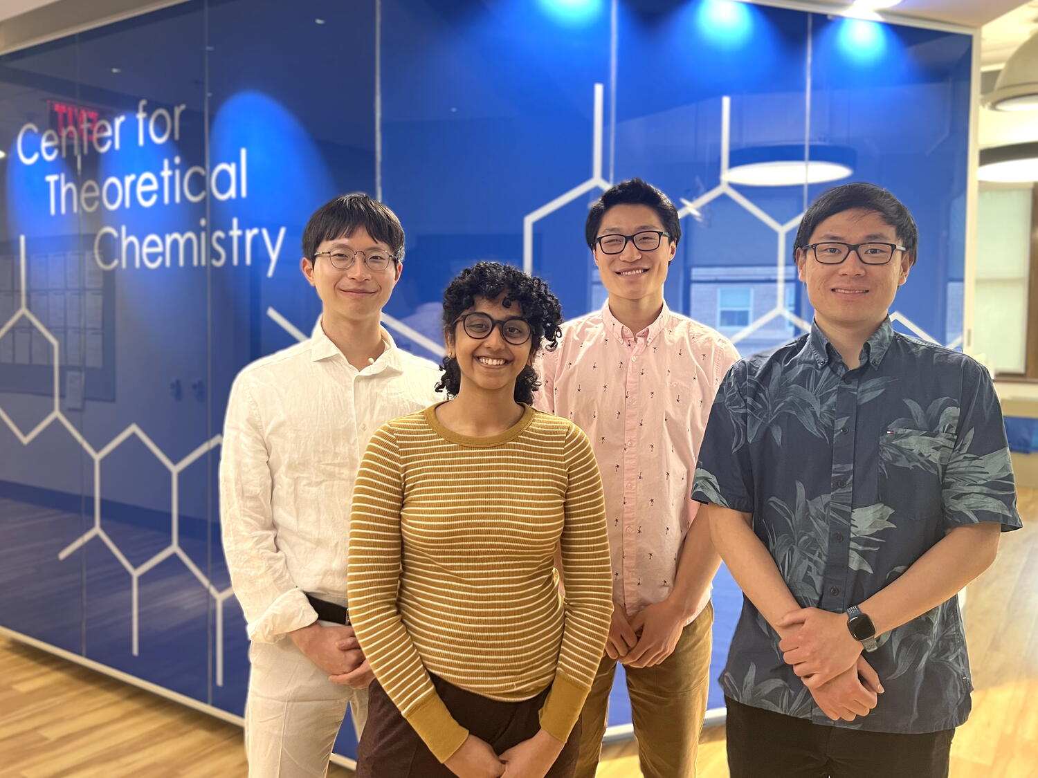 Four researchers stand side by side in front of a blue wall