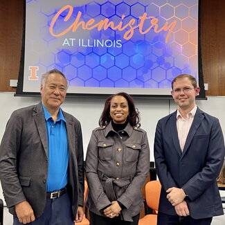 Alan Wu, LaShaunda King-McNeil and Brett McGuire stand side by side in a lecture classroom with a large overhead screen behind them that says Chemistry at Illinois.