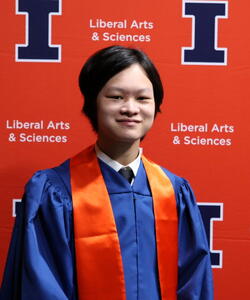 Kenneth Chen in graduation regalia in front of an orange Block I banner.