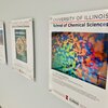 Framed prints of winning images in the SCS Science Image Challenge hang on a white wall at Willard Airport in Savoy.