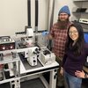 Professor Hee-Sun Han, right, and grad student Alex Schrader stand next to automated microscopic equipment they created. 