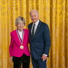 Photo of Mary-Dell Chilton standing next to President Joe Biden in front of a gold curtain with a medal around her neck in a ceremony at the White House.