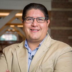 Head and shoulders photo of Joaquin Rodriguez Lopez smiling, looking into the camera wearing a sport coat and button-down shirt