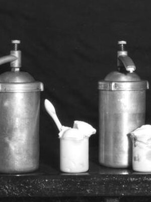 Black and white photo of steel pump cans containing whip cream.