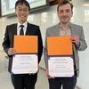 Daniel Hu and Joe Lastowski stand side by side holding award certificates in front of them.
